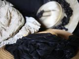 un bol en bois recouvert d'un tissu noir, sur lequel est posé un chapeau