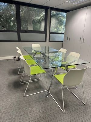 a glass table with four chairs in a conference room