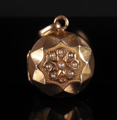 a close up of a gold pendant with pearls on a black surface