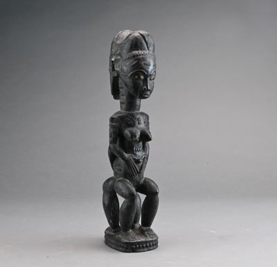 une sculpture noire représentant une femme tenant un bébé dans ses bras