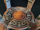 une chaise en bois dont l'assise est ornée d'un motif métallique