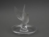 un oiseau en verre posé sur une assiette en verre
