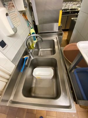 a stainless steel sink in a kitchen with a blue trash can