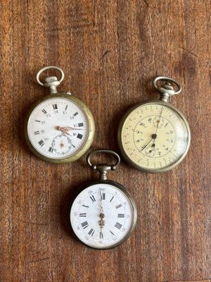 three different types of pocket watches on a wooden surface