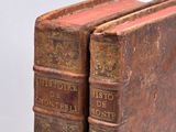 two old books sitting on top of each other on a table