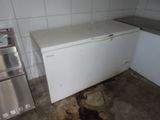 a small white refrigerator in a dirty kitchen with dirty floor
