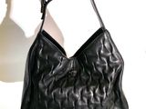 un sac à main en cuir noir suspendu à un crochet sur un mur blanc