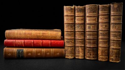 several old books stacked on top of each other on a table