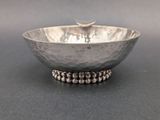 an image of a silver bowl with beads on it