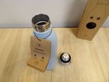 a bottle and a canister on a table next to a cardboard box