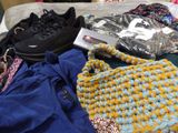 a pile of clothing on a bed next to a pair of shoes