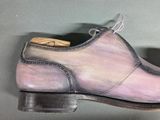 someone is holding a pair of shoes with a tie on them