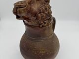 un vase marron orné d'une tête de chien