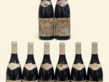 six bottles of wine are lined up on a white surface