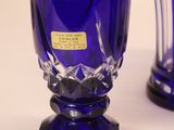 two blue glass vases sitting next to each other on a table