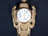 une horloge dorée sur fond noir, ornée d'un oiseau
