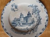 une assiette bleue et blanche sur laquelle est représenté un château