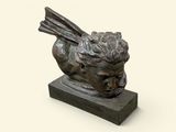 statue d'un oiseau posée sur un socle en pierre, sur fond blanc