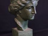 statue of a woman ' s head on a block with a black background