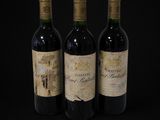 three bottles of red wine sit on a black surface