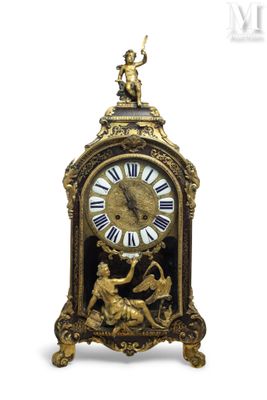 a clock that is sitting on a table with a statue on it