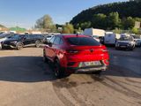 the red car is parked in a parking lot with other cars