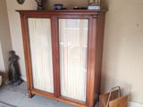 une armoire en bois dans un coin d'une pièce où se trouve un tapis bleu