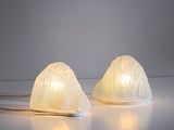 une paire de lampes en verre blanc posées sur une surface blanche, avec un fond blanc