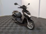 un scooter noir garé dans une pièce au sol à carreaux