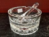 un cendrier en verre contenant une cuillère, posé sur une table