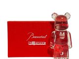 un ours en verre qui se tient debout devant une boîte rouge