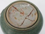 a close up of a green vase with a white lid