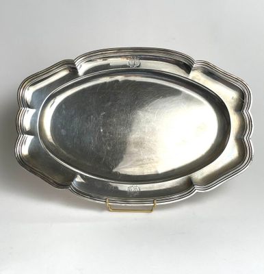 an antique silver plate with a scalloped edge on a white surface