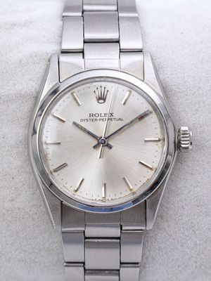 une photo d'une montre Rolex argentée posée sur une surface blanche
