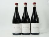 trois bouteilles de vin rouge sont alignées sur une surface blanche