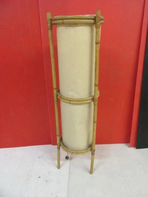 a tall bamboo planter on the floor next to a red wall