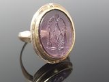a close up of a gold ring with a purple stone in the center