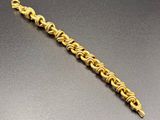 a close up of a gold bracelet on a black surface