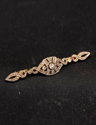 un gros plan d'une broche en or et diamants sur fond noir