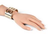 gold metal cuff bracelet on a mannequin hand on a white background