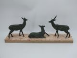 three bronze deer figurines sitting on a wooden base