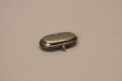 an old silver pill case sitting on top of a white table