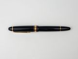 a black and gold fountain pen on a white surface