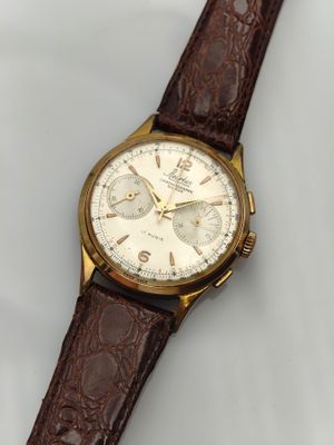gros plan d'une montre sur une surface blanche avec un bracelet marron