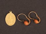 two gold earrings and a gold coin on a black surface