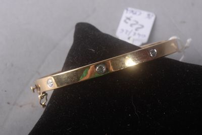 bracelet plaqué or orné de pierres multicolores, posé sur un coussin