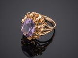 a gold ring with an oval amethorate stone surrounded by small flowers