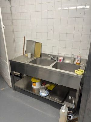 a kitchen with a sink and a trash can in it