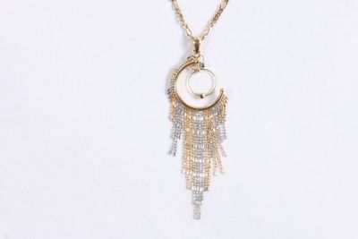 Le collier est composé de chaînes en or et d'un coquillage blanc auquel est suspendue une chaîne.