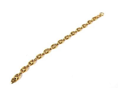 gros plan d'un bracelet en chaîne en or sur une surface blanche